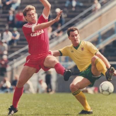 Vintage photo of Canadian soccer player in mid air and a player in a yellow uniform with soccer ball